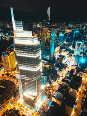 Aerial night view of Ho Chi Minh City skyline with glowing skyscrapers and neon lights, Drone panorama of Saigon downtown, illuminated towers and busy streets of vibrant city