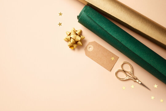 Gift wrapping materials. Rolls of wrapping paper, ribbon, label. Beige background, space for your text. Preparing for the holidays