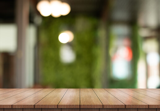 Empty wooden table top with lights bokeh on blur restaurant background.