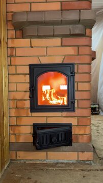 A newly built stove. A test fire is burning in the firebox. The flame is visible through the glass in the firebox door. Construction of a heating stove. Vertical video.