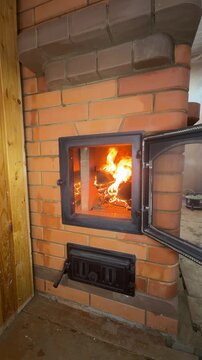 A newly built stove. The firebox door is open, a test fire is burning inside. Construction of a heating stove. Vertical video.