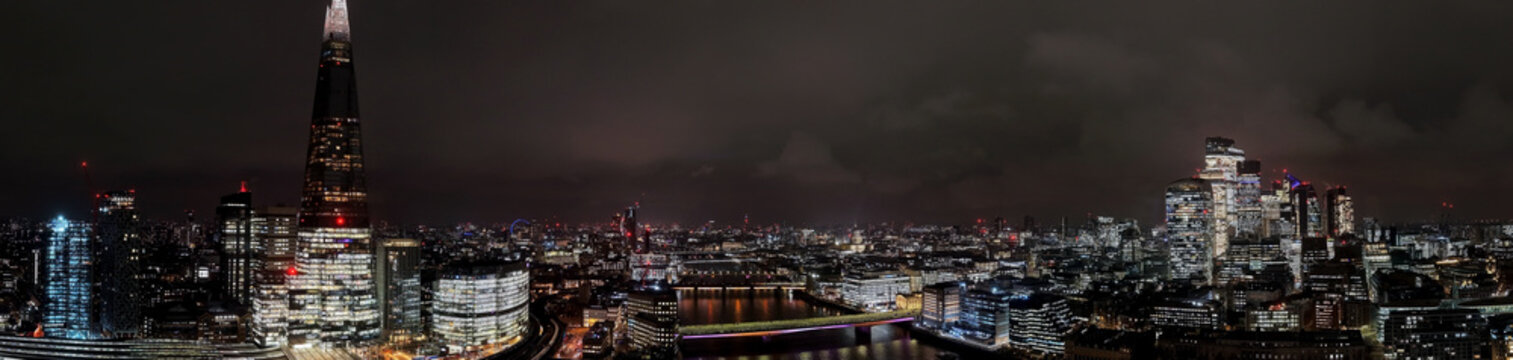 Night aerial shot of The Shard skyscraper in London, United Kingdom.  Aerial drone view of capital cityscape at night 