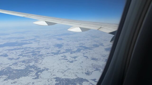 Airplane wing view of snowy fields and rural roads in winter