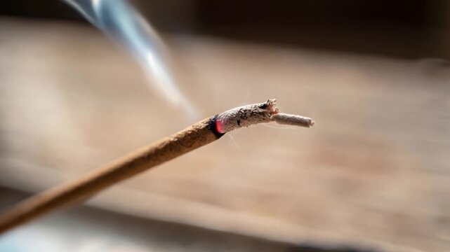 Macro shot of a burning incense stick with smoke in a peaceful atmosphere