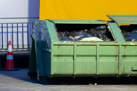 green dumpster filled with resident debris. Dumpsters being full with garbage container Over flowing.
