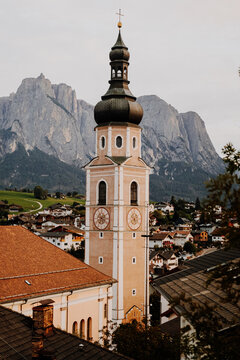 Ancient religious frescoes on the exterior wall of St. Valentin church with wooden benches, South Tyrol, Italy