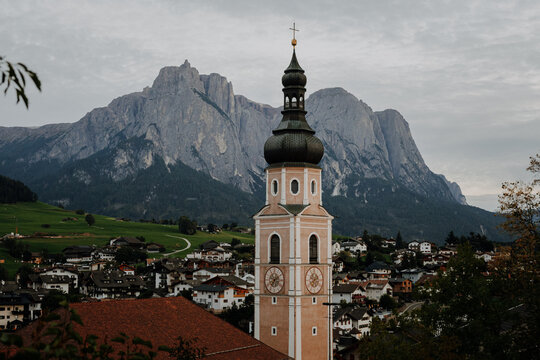 Ancient religious frescoes on the exterior wall of St. Valentin church with wooden benches, South Tyrol, Italy