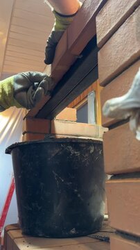 A stove master at work. Lays brick on a lintel made of angle irons. Creates a niche for the cooktop of a heating stove. Smoke channels and reinforced brick masonry are visible.