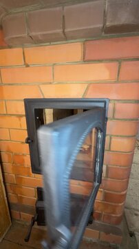 A stove master gives a tour of the newly built stove. Opens the firebox door, demonstrating the firewood arranged for lighting a test fire. Construction of a heating stove. Vertical video.