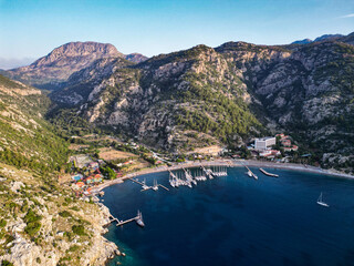 Obraz premium Aerial view of Mediterranean coastal town between mountains with boats in turquoise bay