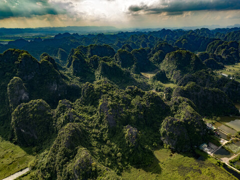 Aerial view of dramatic limestone karst mountains rising from lush green landscape in Ninh Binh, Vietnam
