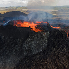 Aerial view of Icelandic volcanic eruption with red hot lava flowing down slopes in dramatic lighting