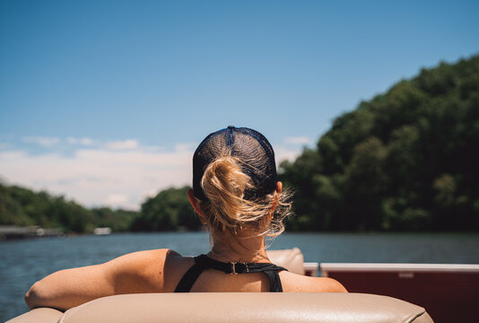Woman sitting on pontoon boat looking at lake and hills