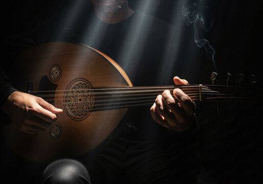Musician playing a traditional wooden Oud instrument in dramatic lighting with smoke and light rays.