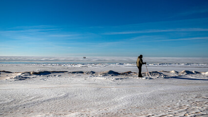 Wonderful view of the frozen sea coast in winter, man walks along the snowy seashore, rocky coast