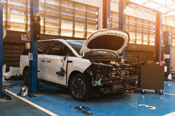 Modern white electric vehicle with side damage in a professional repair service center.