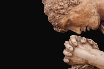 Minimalist vertical portrait of praying stone statue isolated on dark background, representing belief, meditation, and inner peace.