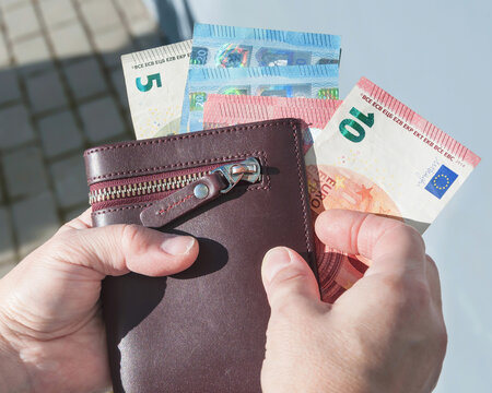 Leather wallet and euro banknotes in a woman's hands, selective focus.	