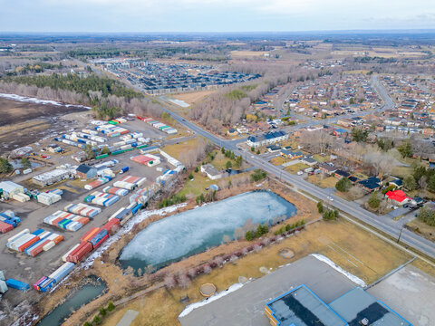 Drone view showing residential housing, commercial industrial storage containers, a frozen pond, and roads illustrating varied land use in barrie, ontario, canada