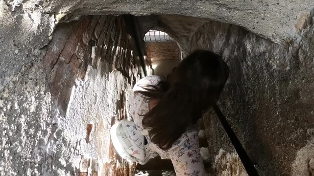 Girl walking down the stone stairs of the civic tower Campanone, Bergamo, Italy.