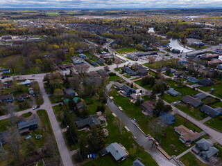 Aerial view capturing the town of georgina, ontario, showing suburban homes, lush green trees, local streets, and water channels with docks leading to lake simcoe under a cloudy sky