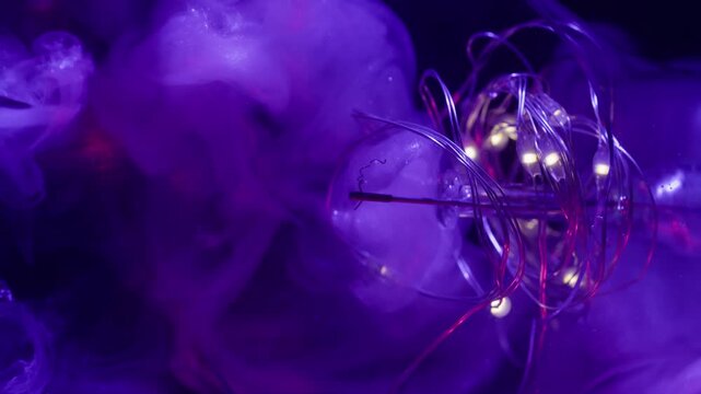 Blur vapor splash. Neon light bulb. Purple violet shiny fluid exploding in broken glass. Garland fume paint color abstract black background.
