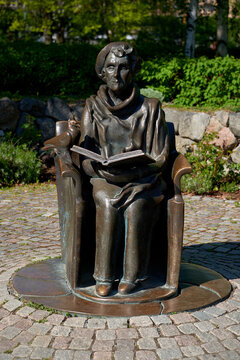 STOCKHOLM, SWEDEN - May 14, 2018: A bronze statue of Swedish author Astrid Lindgren reading a book with a bird on the armrest.