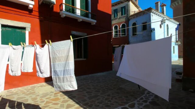 Burano street with laundry washed clothes hanging out to dry on ropes.
