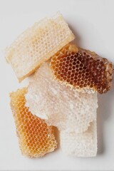 Stack of golden and pale honeycomb pieces isolated on light background. Studio food photography.