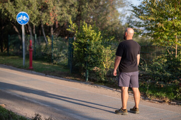 Obraz premium Man Preparing for Workout in City Park. Pre Workout Routine in Green Park. Athlete Getting Ready for Outdoor Training. Healthy Lifestyle –Man Training Preparation. Fitness Preparation Session Outdoor.