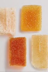 Stack of golden and pale honeycomb pieces isolated on light background. Studio food photography.