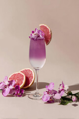 A bright pink cocktail sits in a glass with a salt rim, decorated