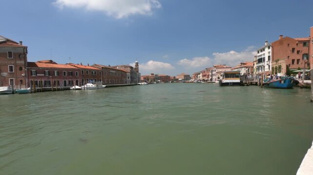 Murano / Venice / Italy - June 23, 2019: WALKING - Fondamenta Marco Giustinian alongside the canal, traffic and moored boats in Murano island, Venice.