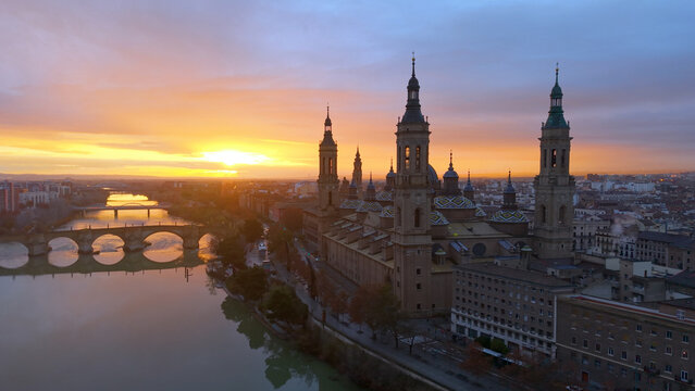 Aerial View Capturing Sunset Glow Illuminating Cathedral Domes And Tranquil River Reflections. Zaragoza. Spain 