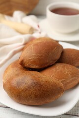 Fototapeta premium Yummy baked patties served with tea on white wooden table, closeup