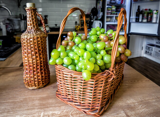 Sweet grape in the basket and wine bottle on the table