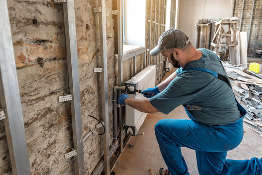 Professional plumber at work. Installing adjusting water heating radiator