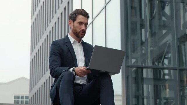 Serious Caucasian mature business man talking video call in city online teacher mentor talk internet class course in downtown businessman sitting communicating virtual interview with laptop computer