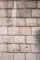 Fototapeta premium Close up of textured limestone brick wall with rough surface and visible mortar lines. Natural stone pattern creates a neutral architectural background.
