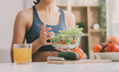 Fit young Asian women in activewear sitting on yoga mat and eating fresh vegetable salad after workout, representing clean eating, fitness lifestyle, wellness routine and health balance. © ARMMY PICCA