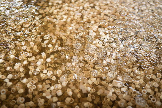 Small hexagonal pasta pieces in boiled liquid
