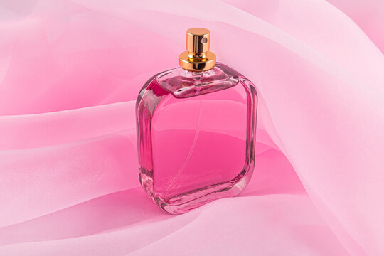 Elegant perfume bottle against pink organza fabric