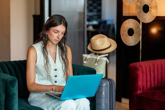 Woman working on laptop in modern hotel lobby