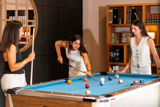 Women playing pool in a stylish indoor setting