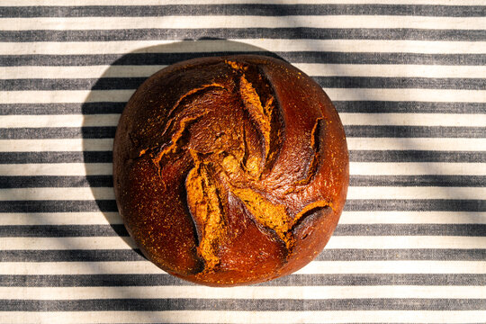 Crusty round bread on striped cloth background