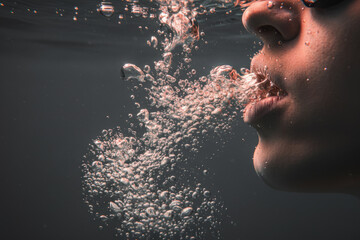 Close up profile of swimmer face exhaling air bubbles underwater representing breathing technique or drowning struggle concept suitable for sports training or abstract art background