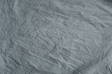 Close-up texture of heavily crumpled gray fabric with deep creases, fine weave, and soft shadows creating tactile depth and abstract textile detail.