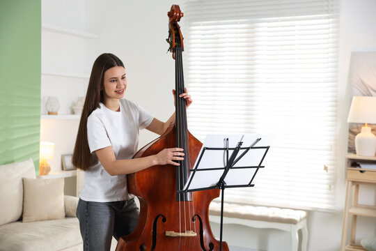 Teenage girl playing double bass at home