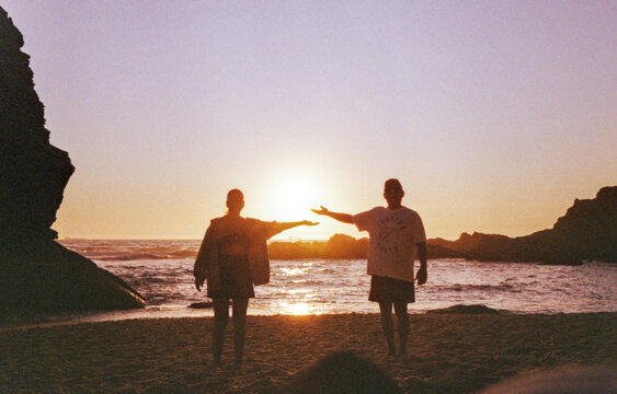 35 mm film photo of couple reaching for the sun at sunset