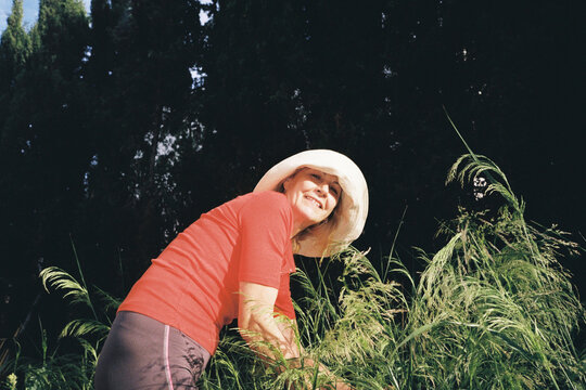 Retired Woman smiling while gardening in tall grass
